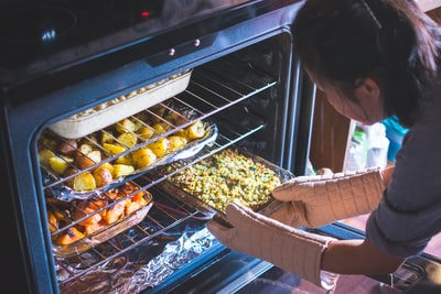 女人把食物放在烤箱里